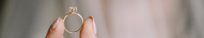 Hand holding a gold diamond engagement ring