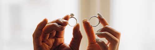 Two hands holding engagement and wedding rings